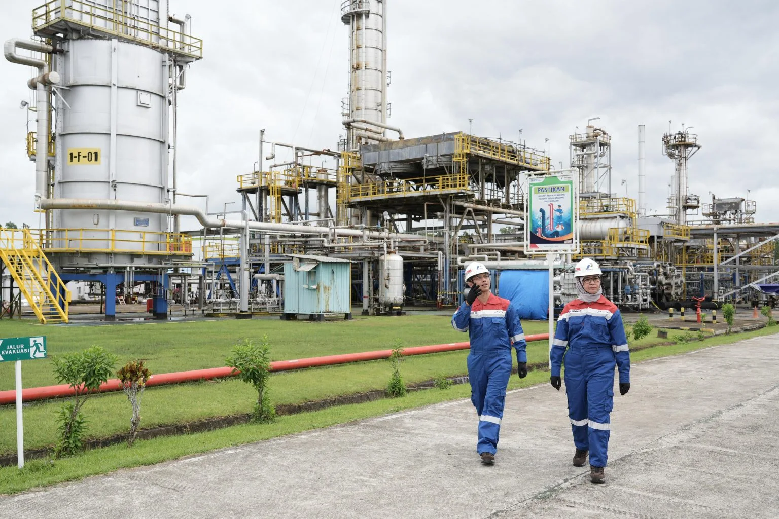 Ilustrasi: Dua pekerja kilang minyak Pertamina berjalan di area fasilitas pengolahan minyak. Foto: Dok. BPH Migas.