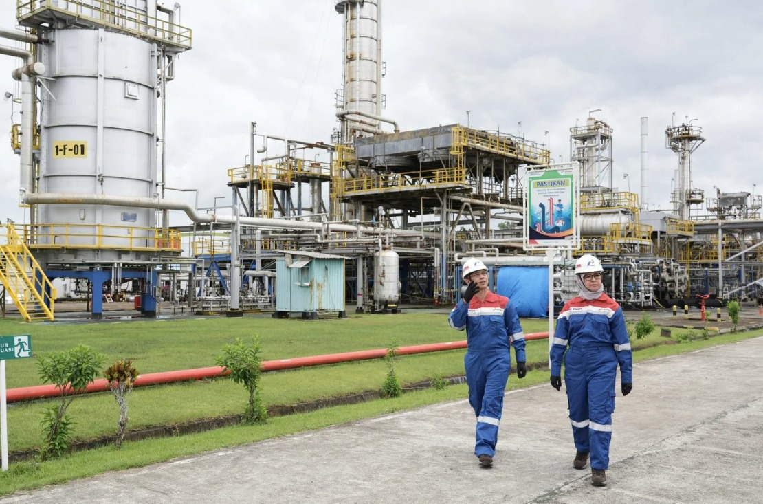 Ilustrasi: Dua pekerja kilang minyak Pertamina berjalan di area fasilitas pengolahan minyak. Foto: Dok. BPH Migas.