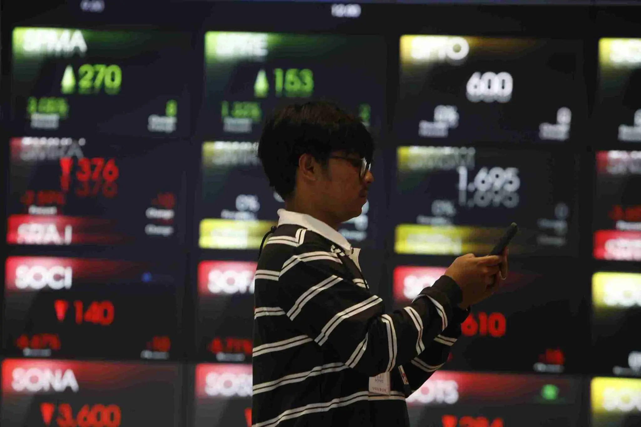Seorang investor melintas di papan pantau Bursa Efek Indonesia. (Foto: KabarBursa/Abbas Sandji)