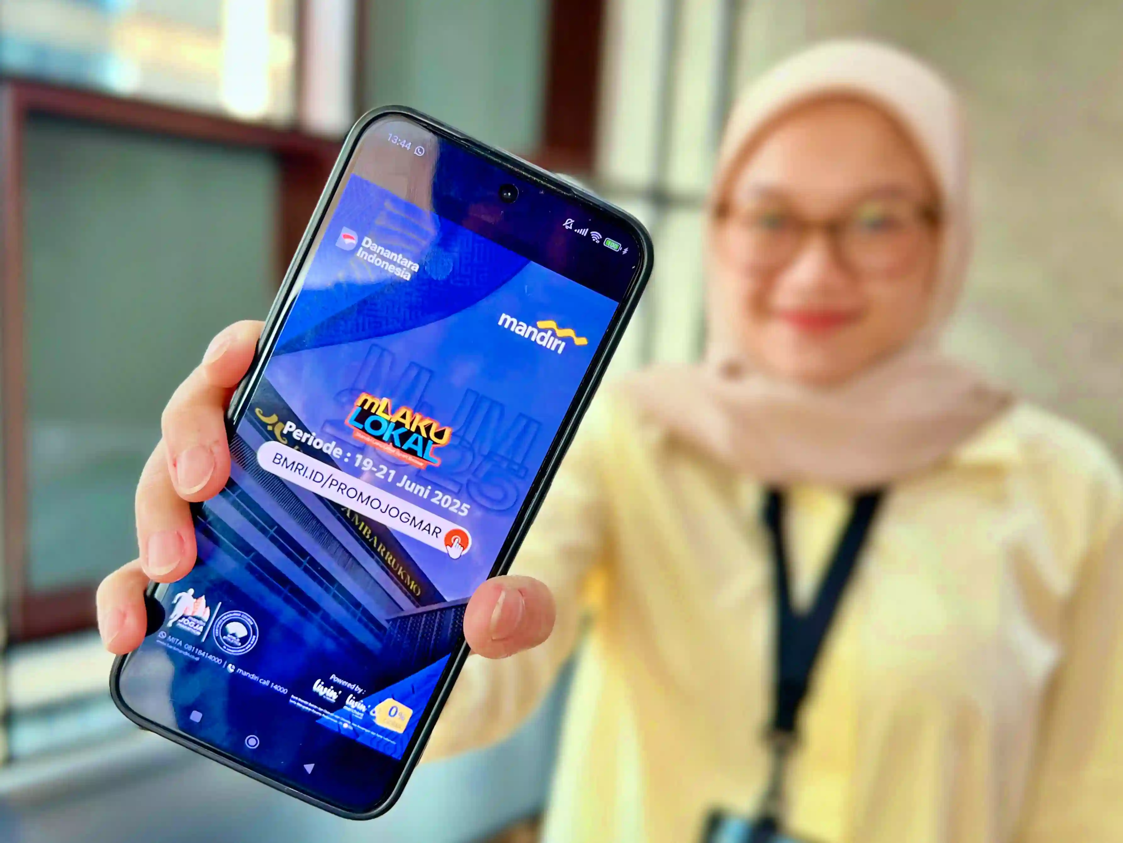 Seseorang tengah menunjukkan handphone yang menampilkan Bank Mandiri turut menawarkan serangkaian program promosi berupa cashback, hadiah, dan diskon belanja. (Foto: Dok. Bank Mandiri)