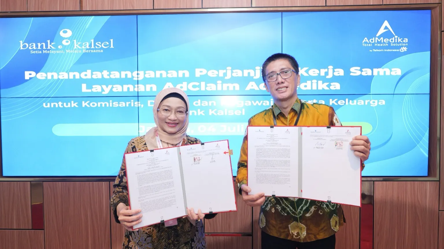 Direktur Utama AdMedika Dian Prambini (kiri) dan Direktur Utama BPD Kalsel Fachrudin (kanan) menunjukkan dokumen Perjanjian Kerja Sama pengelolaan manfaat kesehatan karyawan BPD Kalsel melalui layanan AdClaim, usai penandatanganan di Telkom STO Gambir, Jakarta, Jumat, 4 Juli 2025. Foto: Dok. AdMedika/Telkom.