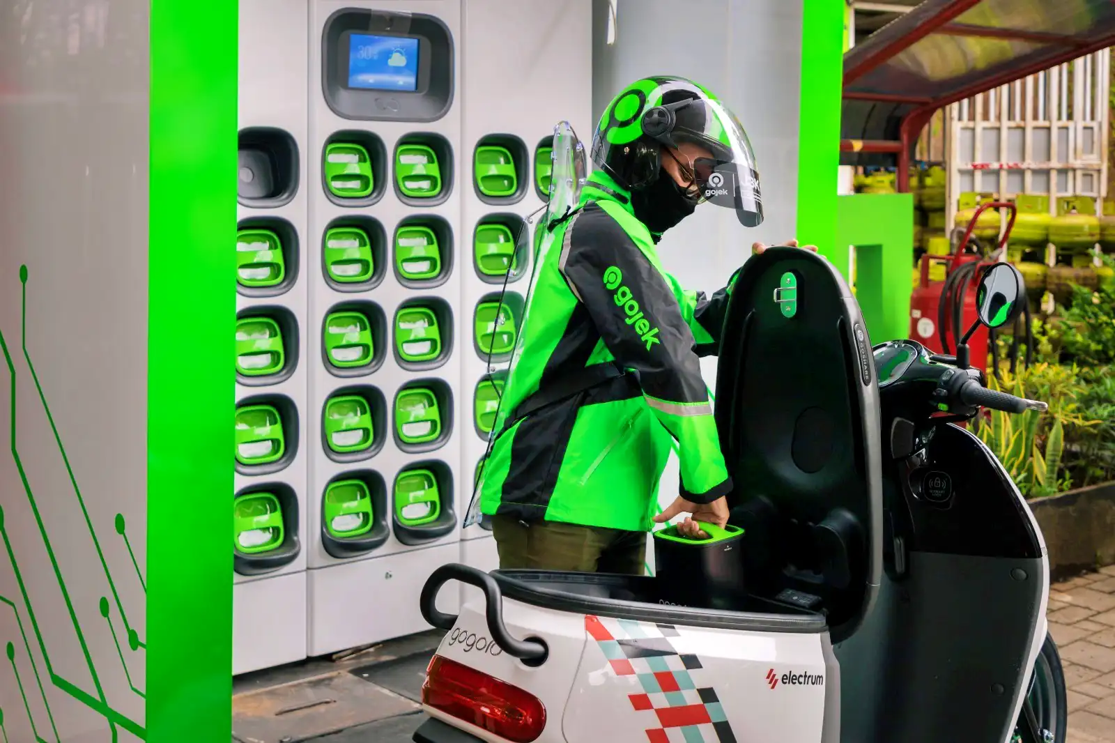 Ilustrasi: Pengendara Gojek tengah mengisi ulang baterai motor listrik. Foto: Dok. GoTo.
