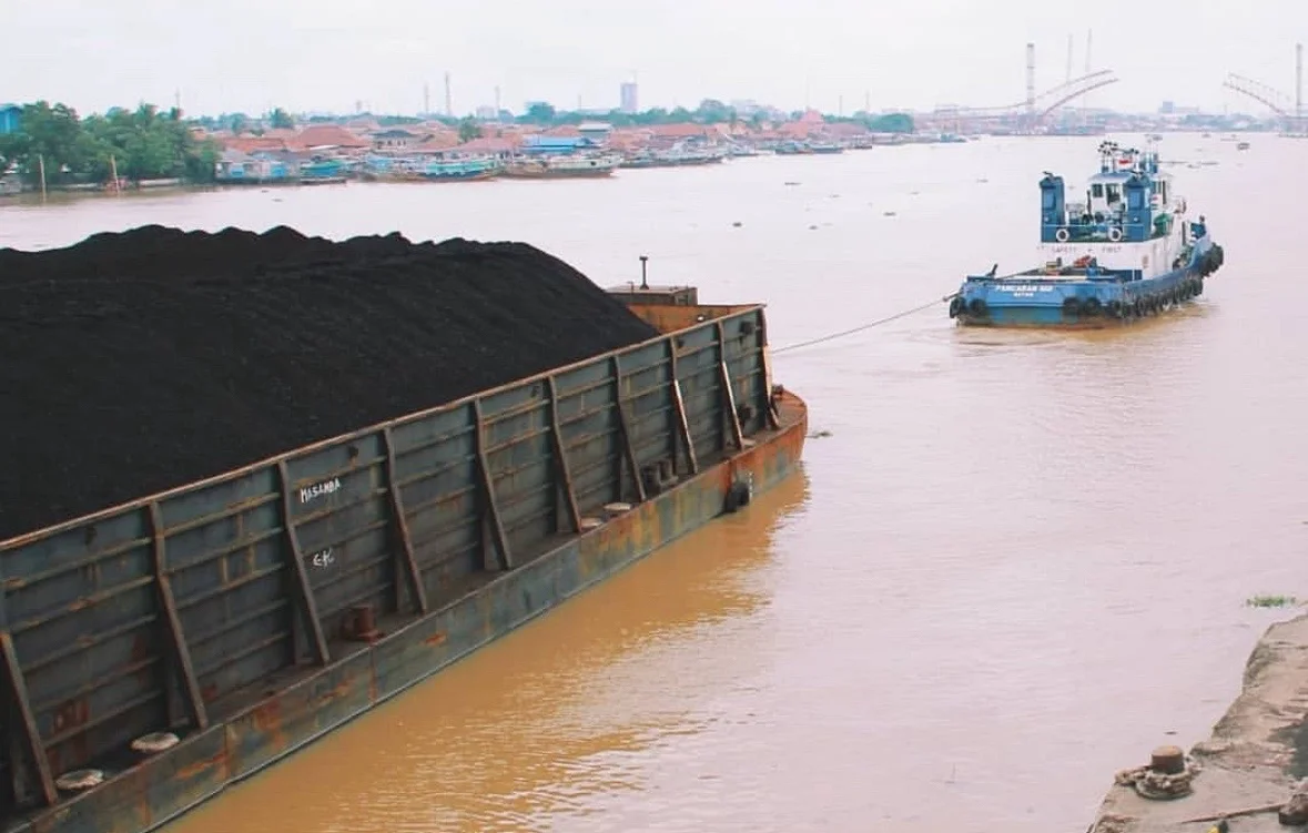 Tongkang bermuatan batu bara milik PT Bukit Asam Tbk (PTBA) ditarik kapal tunda melintasi jalur sungai untuk didistribusikan ke pelabuhan ekspor dan pembangkit listrik. PTBA merupakan salah satu produsen batu bara terbesar di Indonesia. Foto: IG @bukitasamptba