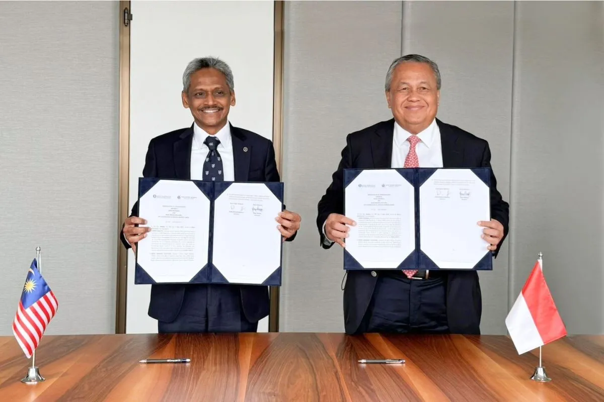 Gubernur Bank Indonesia (BI) Perry Warjiyo dan Gubernur Bank Negara Malaysia (BNM) Dato' Abdul Rasheed Ghaffour menunjukkan lembar nota kesepahaman (MoU). Foto: Dok Bank Indonesia